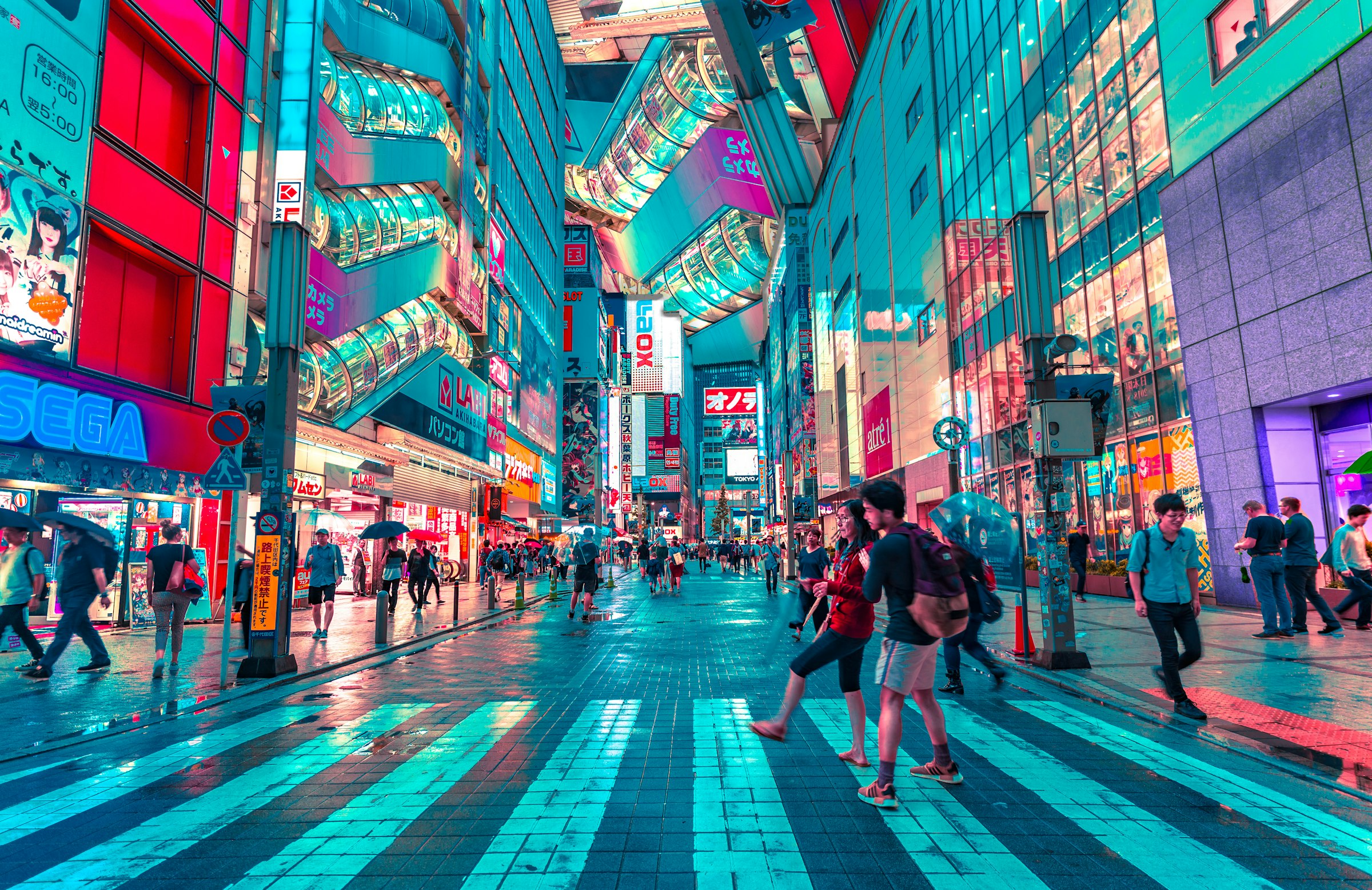 People walking along a brightly lit street in Japan at night